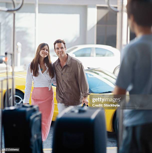 view of a young couple walking with luggage - open roads world premiere of mothers day arrivals stockfoto's en -beelden