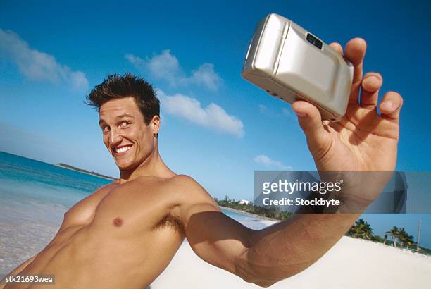 side view of a young man taking a picture of himself using camera - camera picture ストックフォトと画像