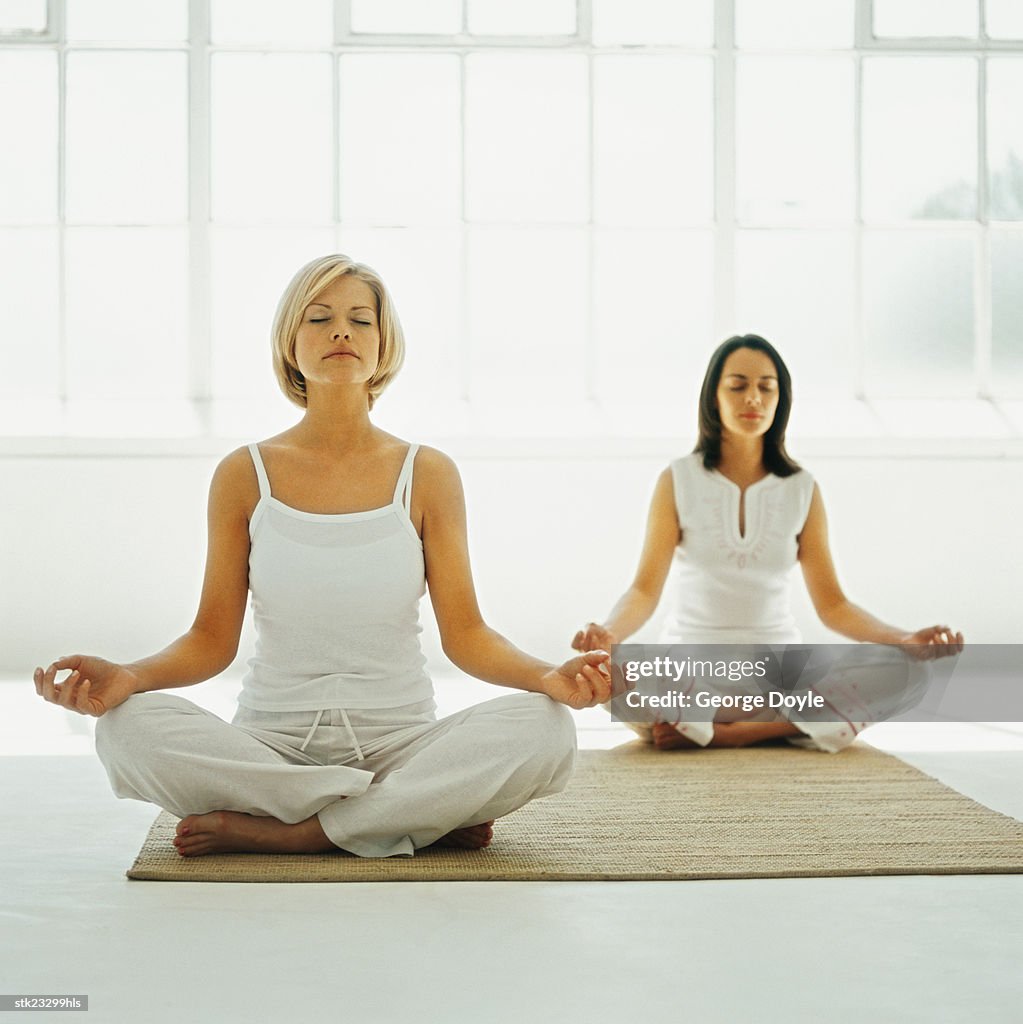 Two women sitting on the floor meditating