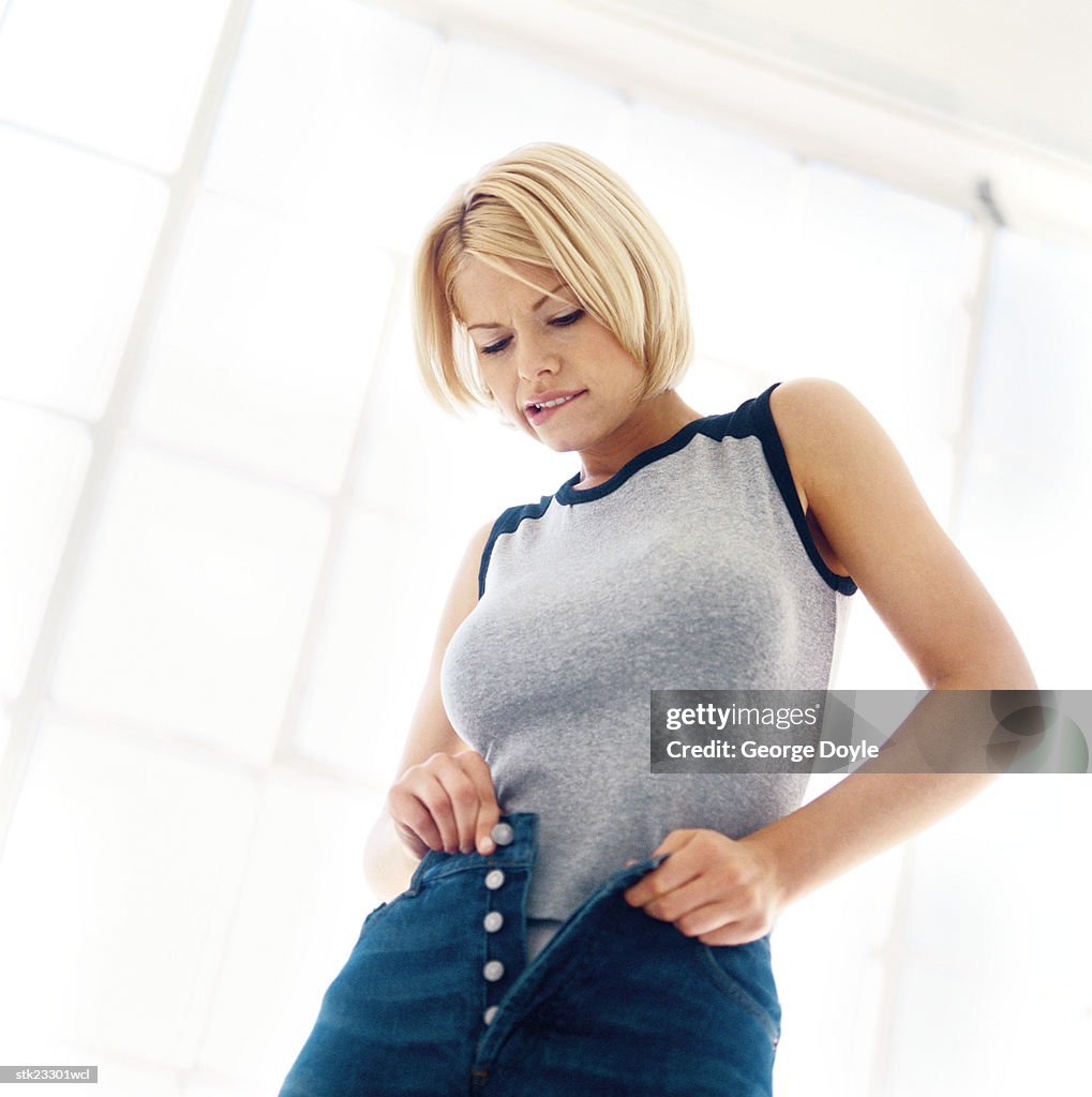 Low angle view of a woman trying to button her jeans closed