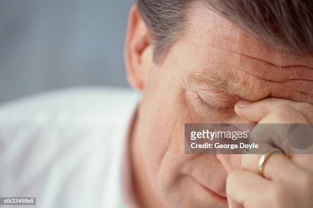 close-up of a man pinching the bridge of his nose - pinching nose stockfoto's en -beelden