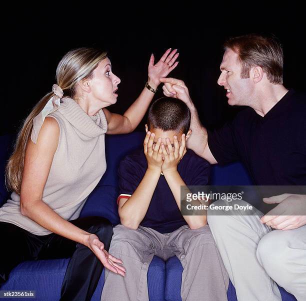 husband and wife fighting  with a child sitting between them - between bildbanksfoton och bilder
