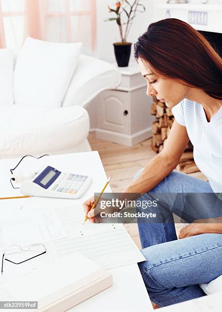 shot of a young woman sitting and doing accounts - duing stock pictures, royalty-free photos & images