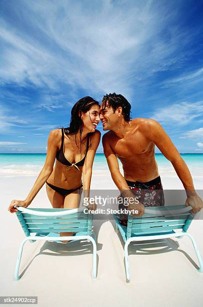 view of a young couple sitting on beach chairs at the beach - clingy girlfriend stock pictures, royalty-free photos & images