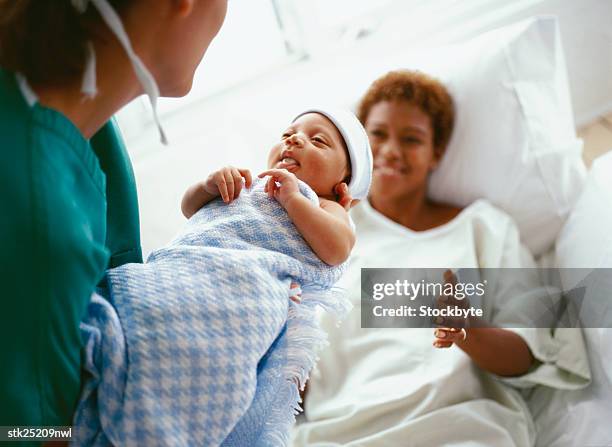 elevated close-up view of a doctor handing a new born baby to the mother - baby close up bed photos et images de collection