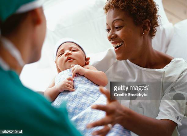 elevated close-up view of a doctor handing a new born baby to the mother - mother holding baby stockfoto's en -beelden