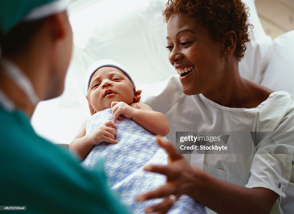 Elevated close-up view of a doctor handing a new born baby to the mother