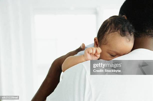 close-up of a baby asleep on father's shoulder - genderblend stock-fotos und bilder