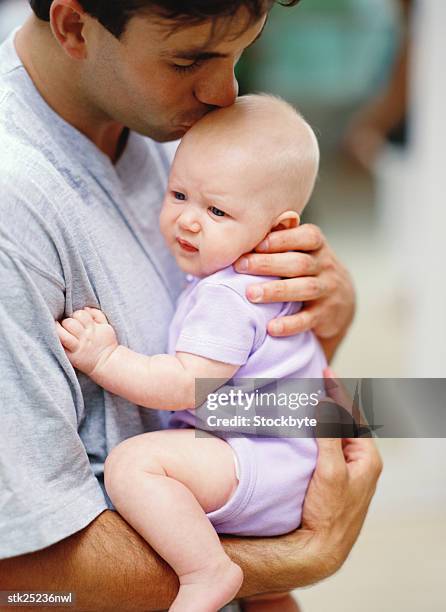 side profile of a father carrying his baby and kissing the head - genderblend stock-fotos und bilder