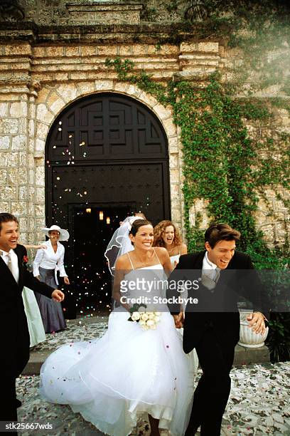 bride and groom running from guests throwing flower petals - bride running stock pictures, royalty-free photos & images
