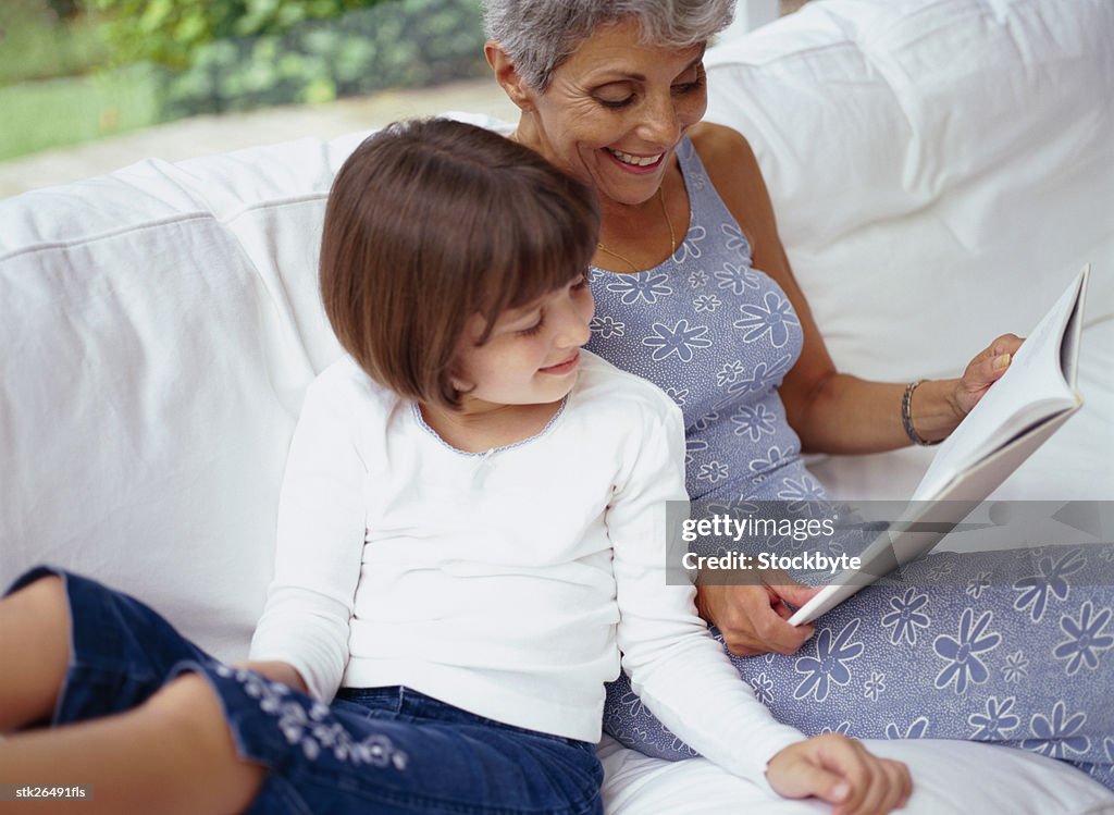 View of an elderly woman reading to her granddaughter (6-8)