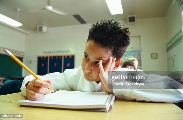 portrait of a schoolboy (8-10) writing in a notebook in class - donald trump holds campaign rally in nc one day ahead of primary stockfoto's en -beelden