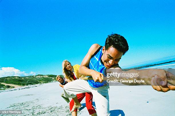 close-up of a man pulling at the rope in a game of tug of war at the beach - george nader stockfoto's en -beelden
