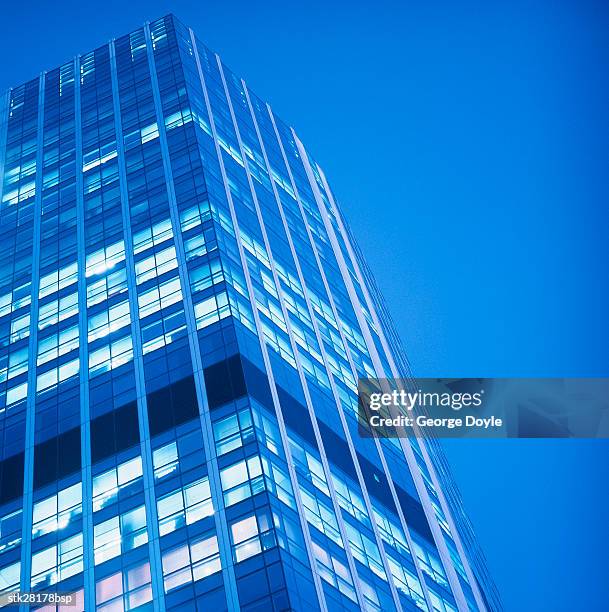 low angle view of a high rise office building at twilight - fensterfront stock-fotos und bilder