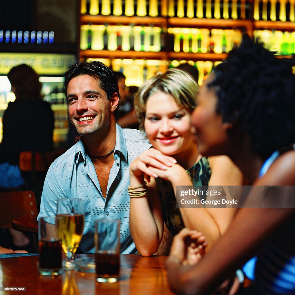 View of two women sitting on a bar table with a man