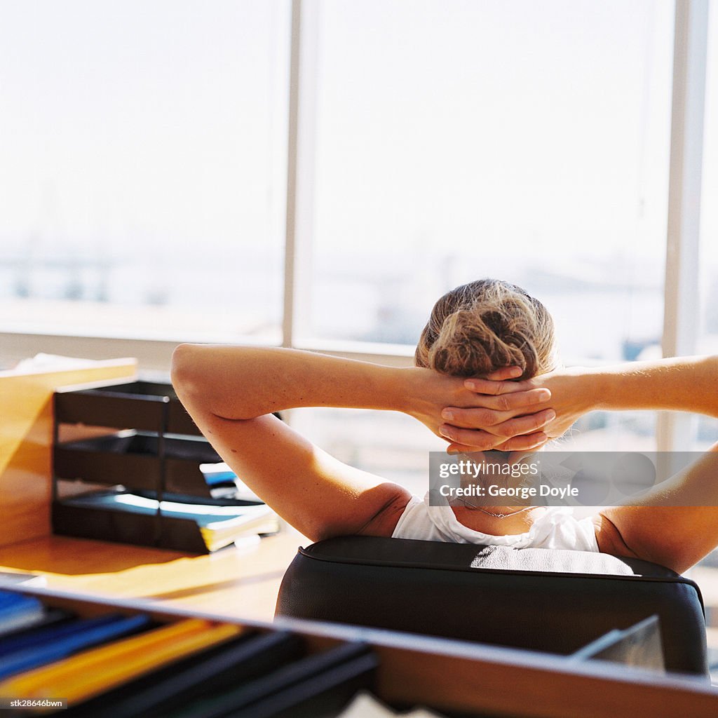 View from behind of woman relaxing at her office desk