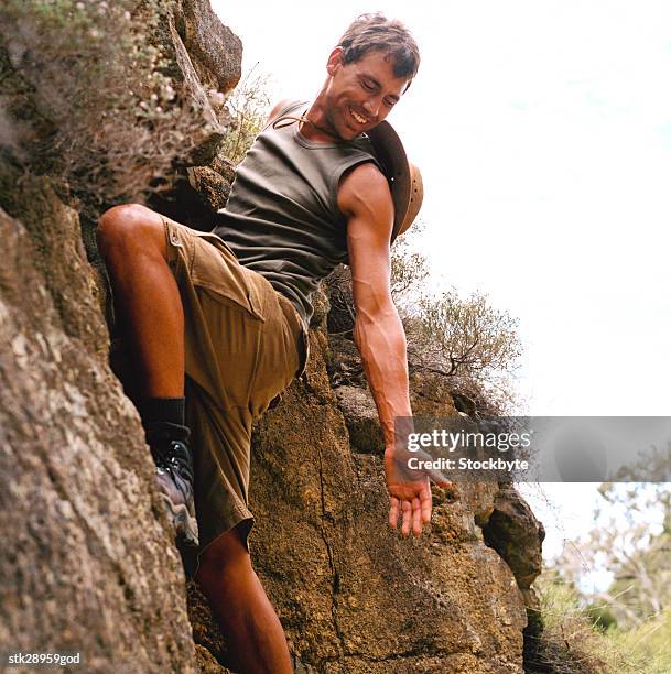 side profile of a young man rock climbing in shorts holding out his hand - brian may signs copies of we will rock you at virigin megastore september 28 2004 stockfoto's en -beelden