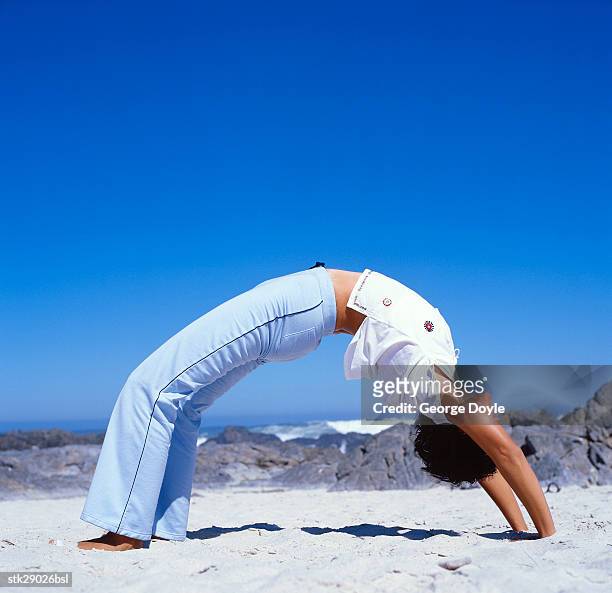 view of a young woman doing yoga at the beach - duing stock pictures, royalty-free photos & images