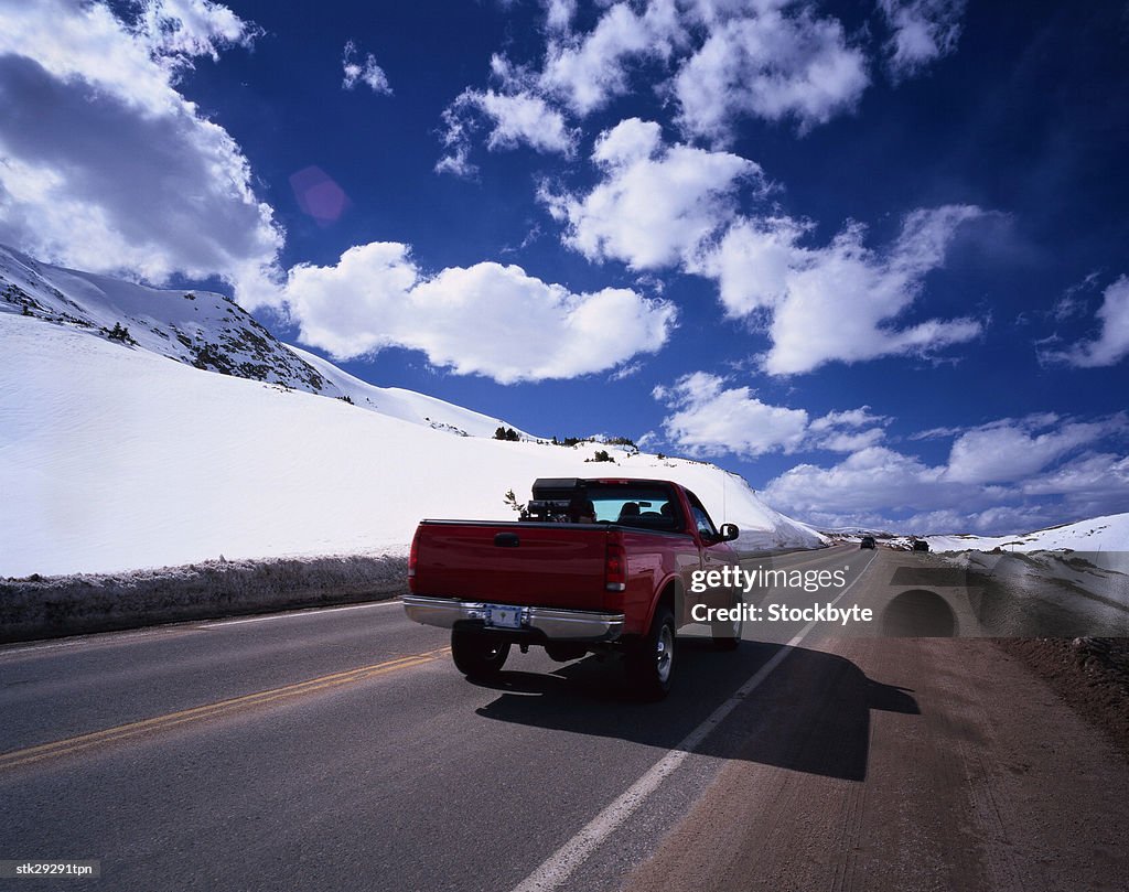View from behind of pickup truck driving on a snow lined street