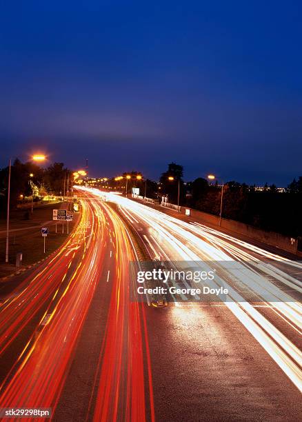 high angle time lapse view of traffic on a city street at night - high street stock-fotos und bilder