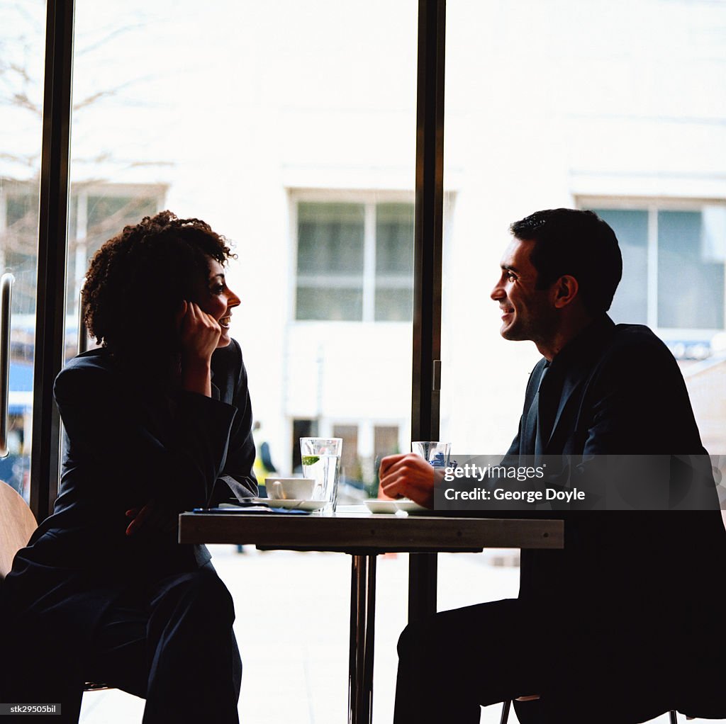 Side profile of a couple sitting across at a table in a caf?