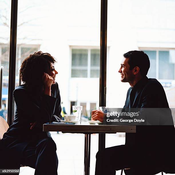 side profile of a couple sitting across at a table in a caf? - across stock pictures, royalty-free photos & images