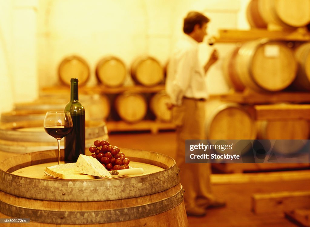 Wine bottle with a wineglass and cheese on a barrel