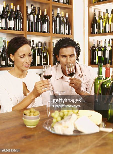 young couple holding wineglasses in a liquor store - liquor stockfoto's en -beelden