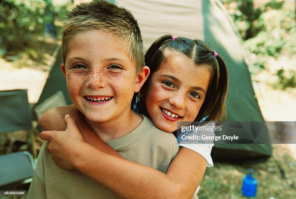 Portrait of a young girl (8-12) with her arms around her brother (8-12)