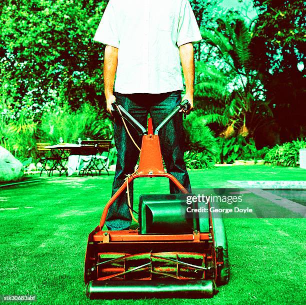 portrait of a young man mowing the lawn with an electric lawn mower - cross entwicklung stock-fotos und bilder