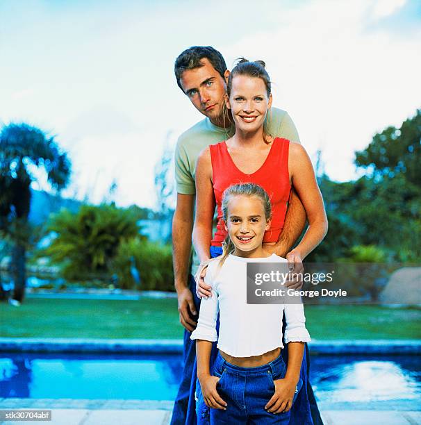 portrait of a young girl (8-10) standing in front of her mother and father - cross entwicklung stock-fotos und bilder