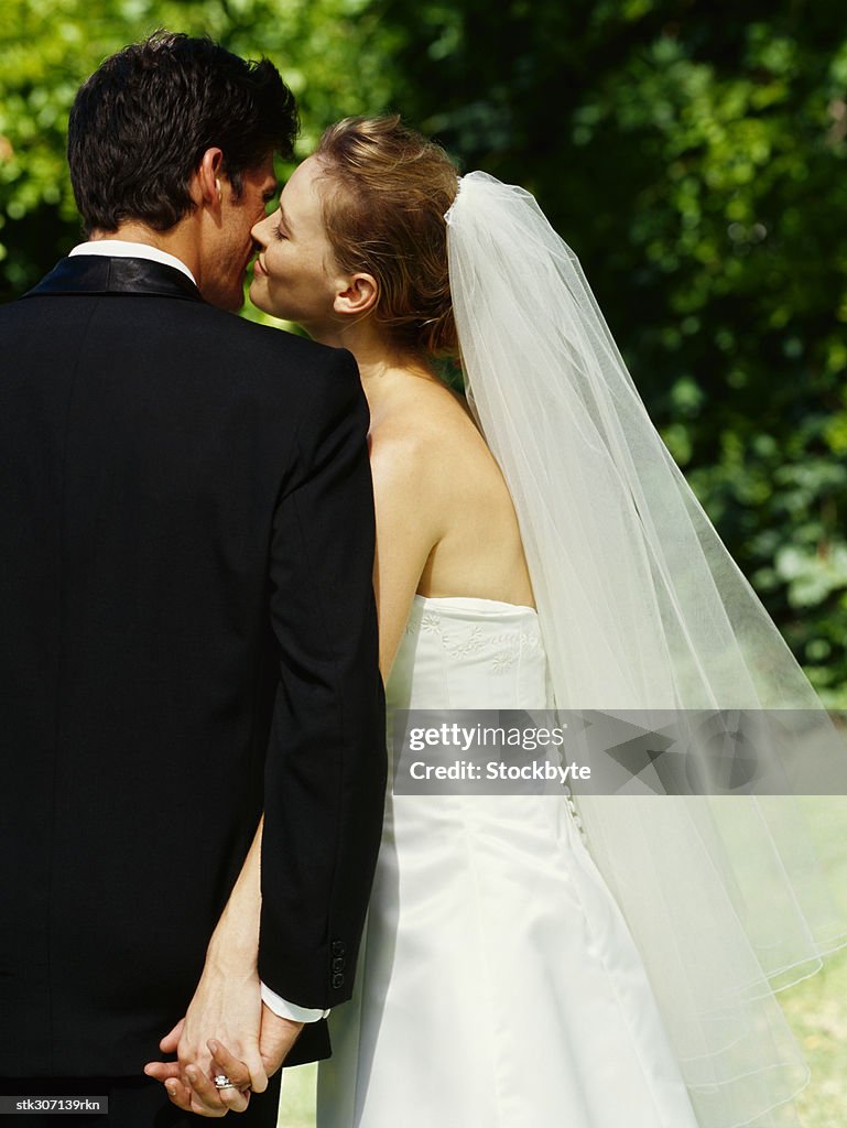 Rear view of a bride kissing her groom