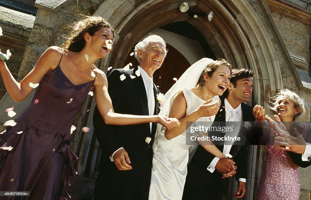 Newlywed couple standing outside a church with their parents and guests