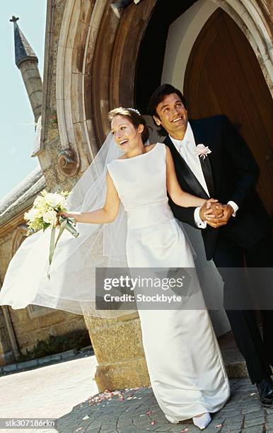 newlywed couple standing outside a church - front on groom and bride stock pictures, royalty-free photos & images