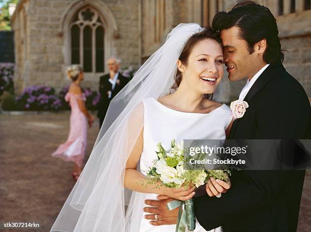 groom whispering in his bride's ear outside a church - whispering stock pictures, royalty-free photos & images