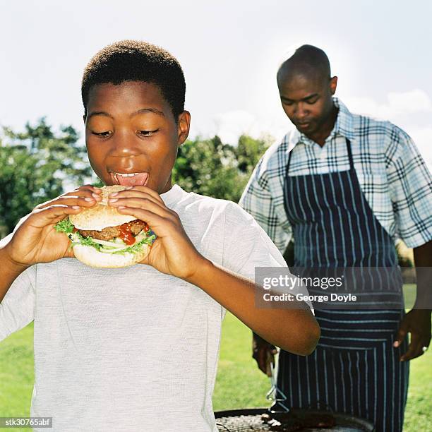 portrait of a young boy (10-14) about to take a bite of a burger - about stock pictures, royalty-free photos & images