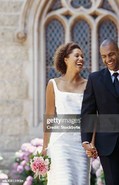 newlywed couple walking outside a church - front on groom and bride stock pictures, royalty-free photos & images