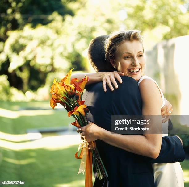 side profile of a newlywed couple embracing each other on a lawn - other stock-fotos und bilder