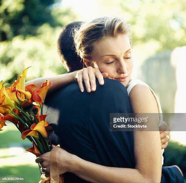 close-up of a newlywed couple embracing each other on a lawn - other stock-fotos und bilder