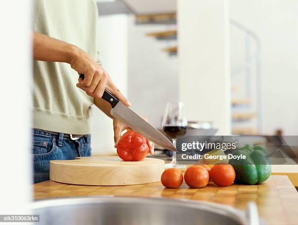 mid section view of a man cutting red bell pepper in the kitchen - bell foto e immagini stock