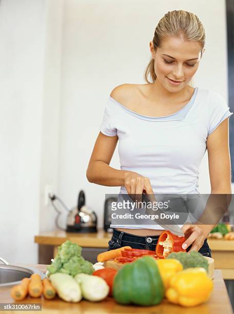 young woman cutting red bell pepper in the kitchen - bell stock-fotos und bilder