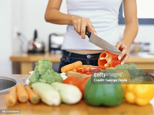 mid section view of a young woman cutting red bell pepper in the kitchen - bell foto e immagini stock