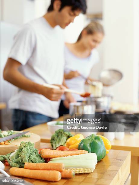 side profile of a young couple cooking food in the kitchen - cruciferae fotografías e imágenes de stock