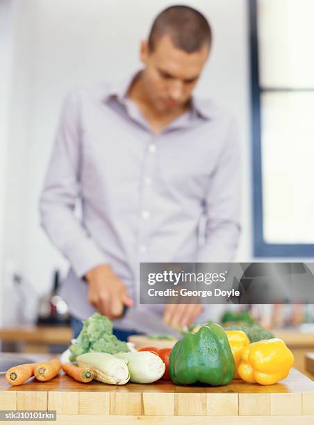 young man cutting vegetables in the kitchen - cruciferae fotografías e imágenes de stock