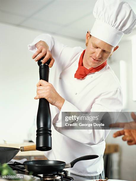 chef holding a pepper mill in the kitchen - pepper mill - fotografias e filmes do acervo