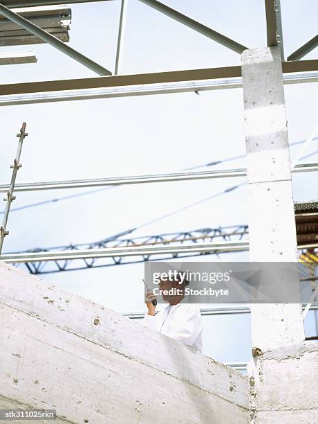 construction worker talking on a walkie-talkie at a construction site - transceiver stock pictures, royalty-free photos & images