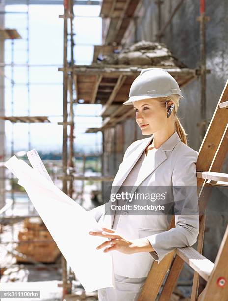 side profile of a female architect holding blueprints at a construction site - inside the link real estate investment trust properties ahead of interim results stockfoto's en -beelden