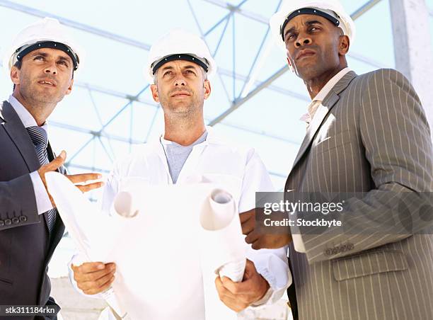 close-up of three male architects discussing a blueprint - swedish royals attend the royal swedish academy of engineering sciences formal gathering stockfoto's en -beelden