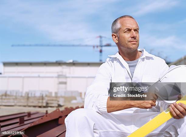 male architect holding a spirit level and a hardhat - hand on knee stock pictures, royalty-free photos & images