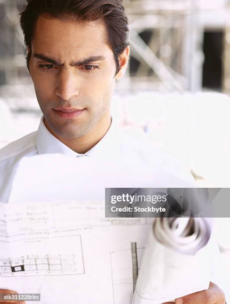 close-up of an architect looking at blueprints at a construction site - trabalho de design imagens e fotografias de stock